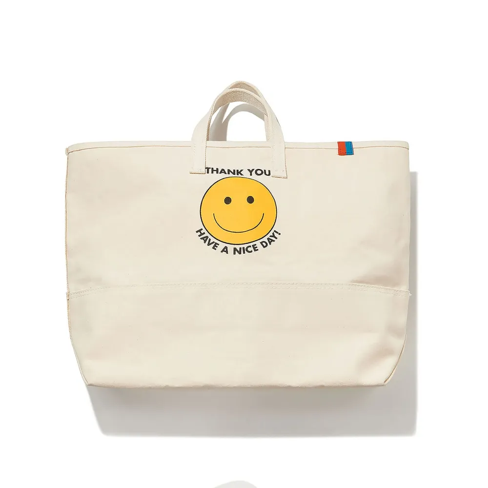 Beige canvas tote bag with yellow smiley face print
