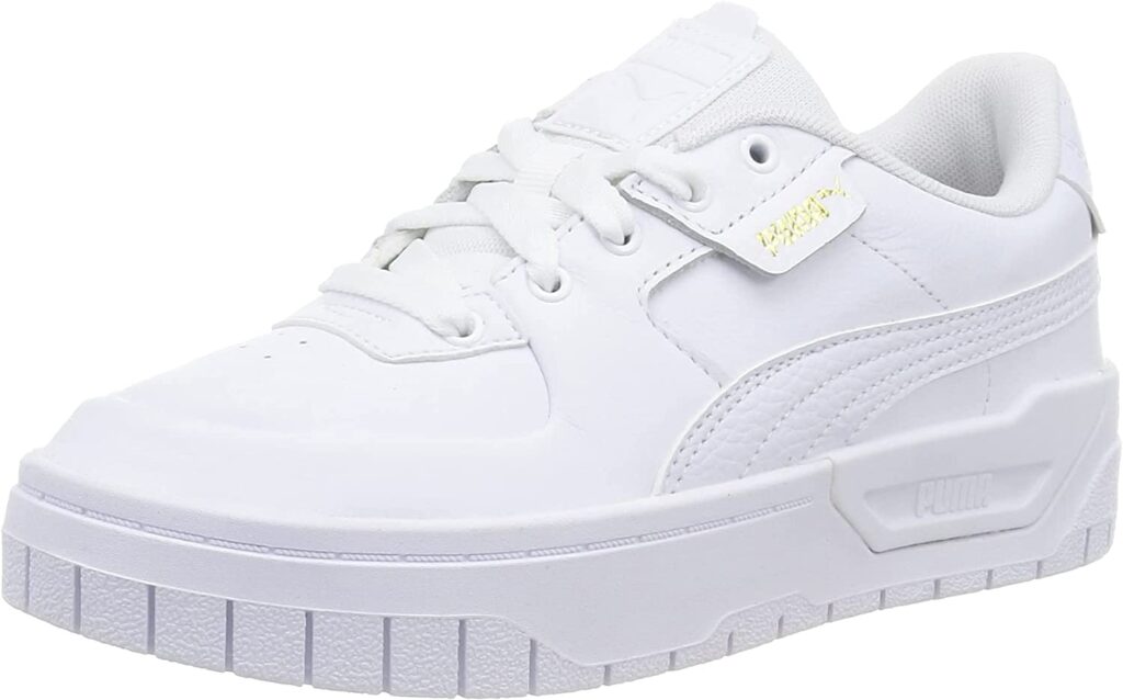 White PUMA tennis shoes with gold accent for women.